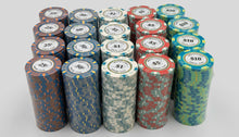 A collection of stacked poker chips in various denominations and colors, including blue, red, green, and gray, arranged on a light-colored wooden table.