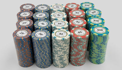A collection of stacked poker chips in various denominations and colors, including blue, red, green, and gray, arranged on a light-colored wooden table.